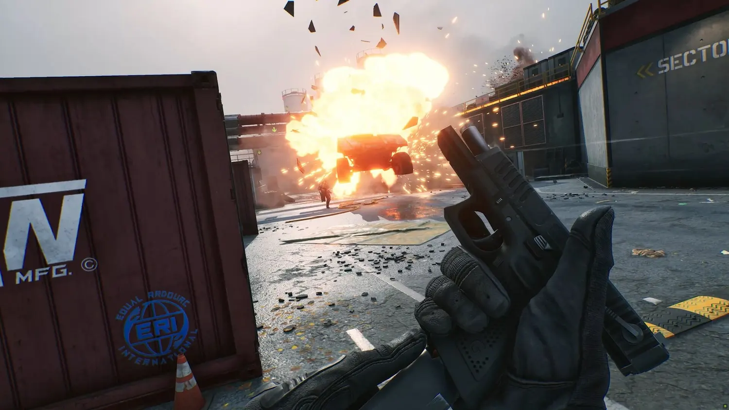 A first-person view in Delta Force of a pistol drawn as a vehicle explodes in an industrial sector